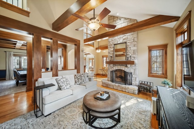living room with a fireplace, wood finished floors, beam ceiling, and ceiling fan