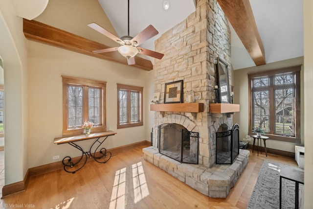 unfurnished living room featuring vaulted ceiling, baseboards, a ceiling fan, wood finished floors, and a stone fireplace
