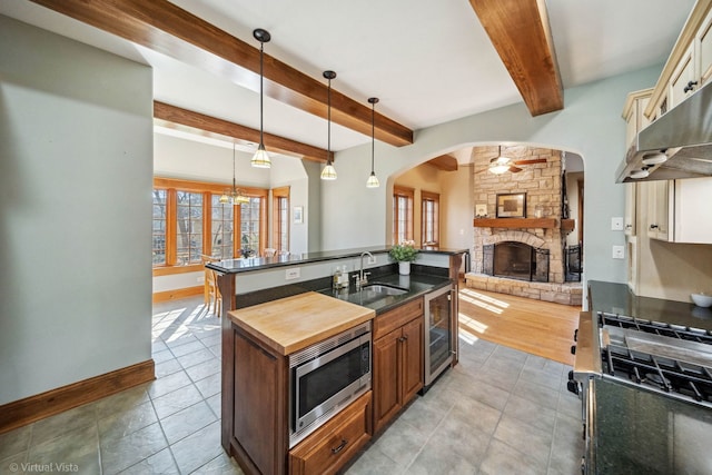 kitchen featuring a stone fireplace, open floor plan, stainless steel microwave, baseboards, and under cabinet range hood
