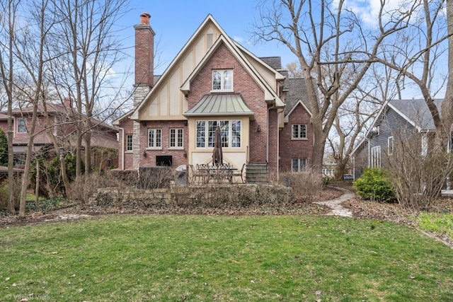 back of house with a lawn, a chimney, stucco siding, brick siding, and a standing seam roof