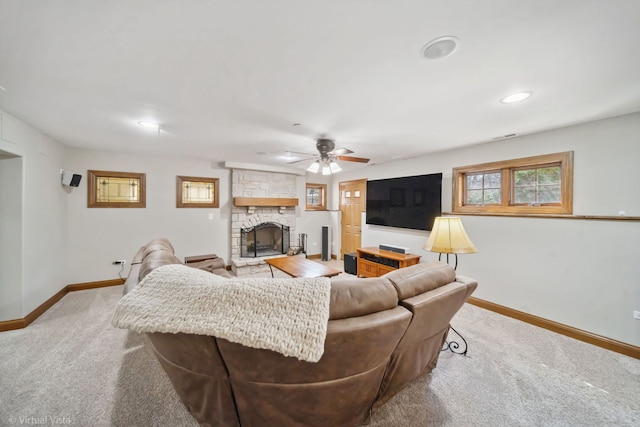 living area featuring baseboards, a stone fireplace, light colored carpet, and plenty of natural light