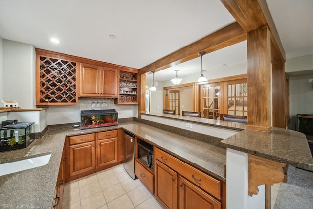 kitchen with brown cabinets, black microwave, dark stone counters, and light tile patterned floors