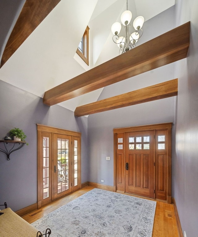 foyer featuring baseboards, beam ceiling, a chandelier, and light wood-style flooring