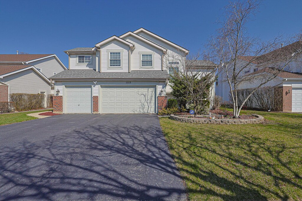 2225 Apple Hill Ln, Buffalo Grove, IL 60089 - traditional home with a front yard, brick siding, an attached garage, a shingled roof, and driveway