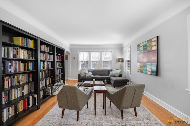 sitting room with arched walkways, light wood-type flooring, and baseboards