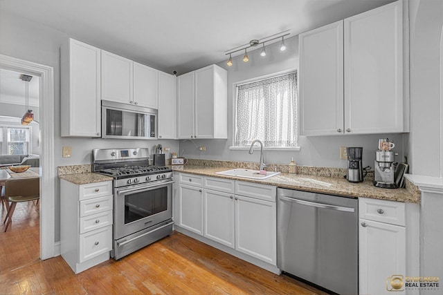 kitchen featuring light stone counters, a sink, white cabinetry, and appliances with stainless steel finishes