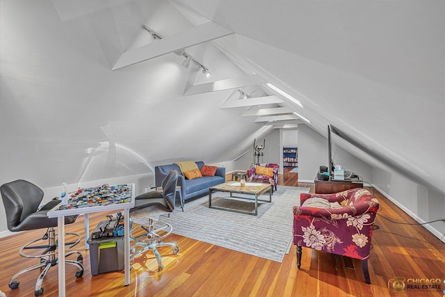 living area with track lighting, vaulted ceiling, and wood finished floors