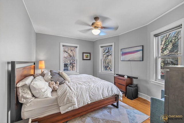 bedroom with ornamental molding, baseboards, multiple windows, and wood finished floors