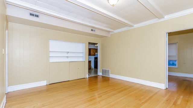 spare room featuring wood finished floors, beam ceiling, and visible vents