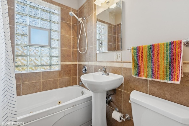 bathroom with tile walls, shower / bathtub combination, a wainscoted wall, and toilet