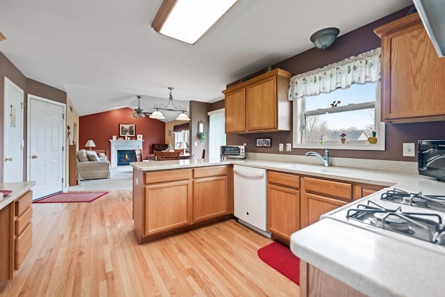 kitchen with light countertops, a sink, white dishwasher, a peninsula, and light wood-style flooring