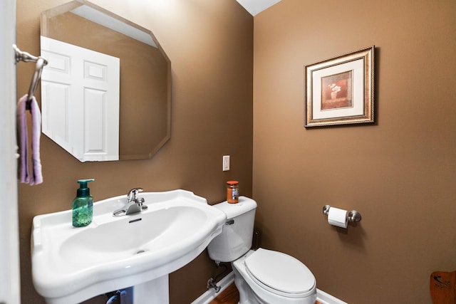 bathroom featuring toilet, baseboards, and a sink
