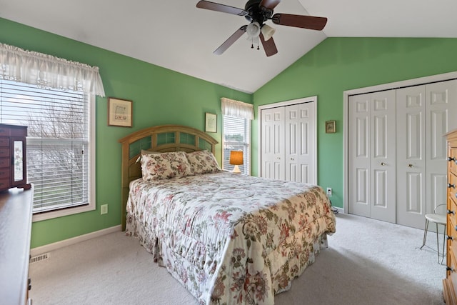 carpeted bedroom with a ceiling fan, multiple closets, baseboards, lofted ceiling, and visible vents