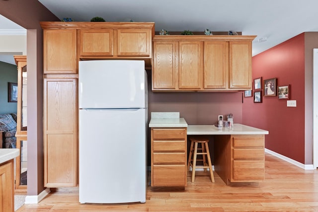 kitchen with baseboards, light countertops, freestanding refrigerator, and light wood-style floors