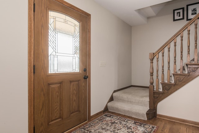 entryway with baseboards, wood finished floors, and stairway