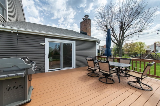 wooden deck with fence, outdoor dining area, a yard, and a grill