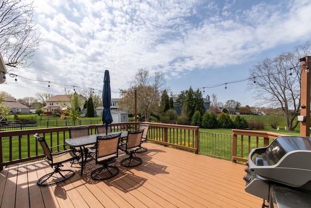 wooden terrace featuring a yard, an outbuilding, outdoor dining space, and a shed