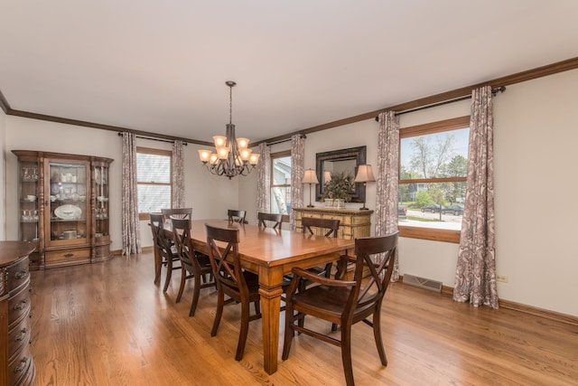 dining space with an inviting chandelier, ornamental molding, visible vents, baseboards, and light wood-style flooring
