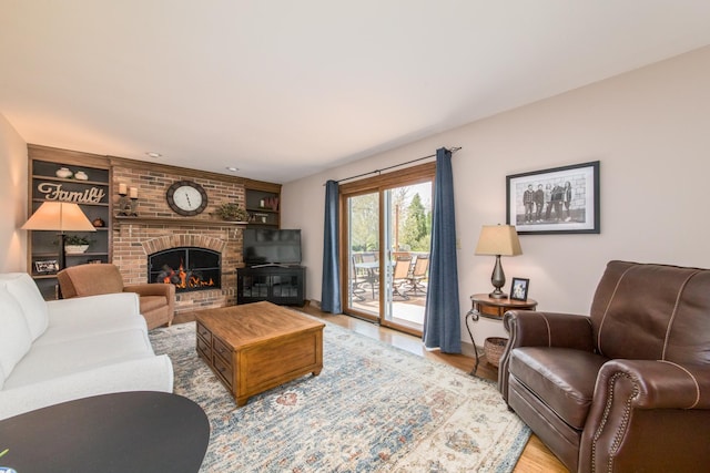 living area featuring built in features, baseboards, a brick fireplace, and wood finished floors