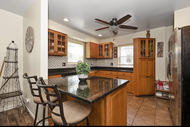 kitchen featuring brown cabinets, decorative backsplash, freestanding refrigerator, and a breakfast bar