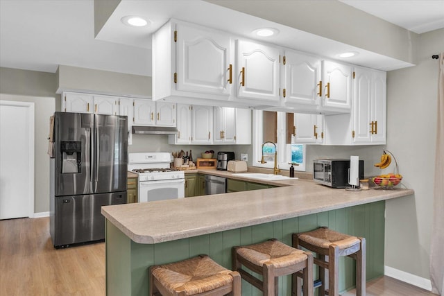 415 E 14th St, Gibson City, IL 60936 - kitchen featuring under cabinet range hood, stainless steel appliances, a sink, a peninsula, and white cabinetry