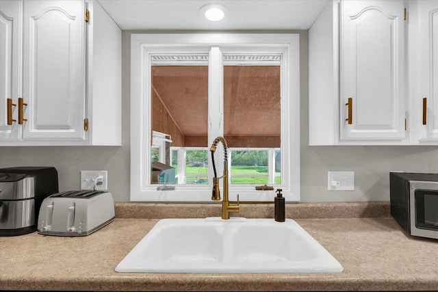 415 E 14th St, Gibson City, IL 60936 - interior details featuring stainless steel microwave, white cabinetry, a sink, and light countertops