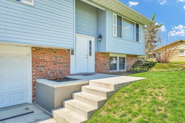 2 Woodland Dr, White Heath, IL 61884 - doorway to property featuring brick siding, a garage, and a yard