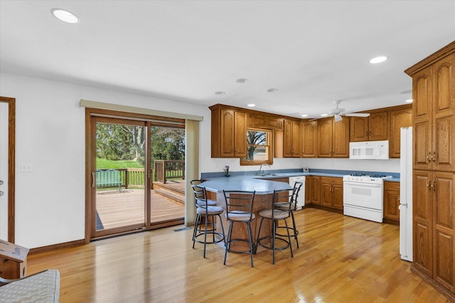 2 Woodland Dr, White Heath, IL 61884 - kitchen featuring white appliances, a sink, a breakfast bar area, a peninsula, and ceiling fan