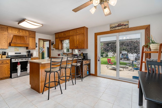 918 Dawes Ave, Joliet, IL 60435 - kitchen with stainless steel range with gas cooktop, custom exhaust hood, brown cabinetry, and a peninsula