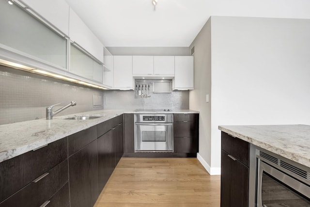 kitchen featuring modern cabinets, white cabinets, a sink, stainless steel appliances, and backsplash