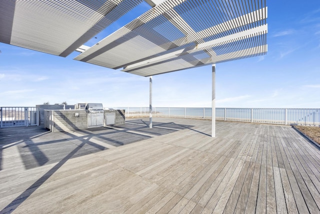 wooden terrace with a water view, fence, and exterior kitchen