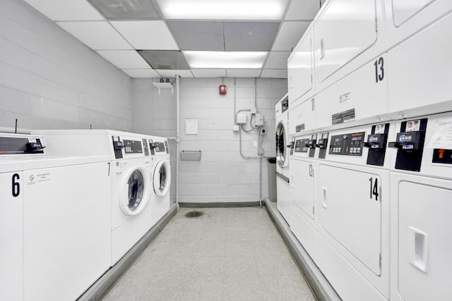 common laundry area with light floors, washing machine and clothes dryer, concrete block wall, and stacked washer and clothes dryer