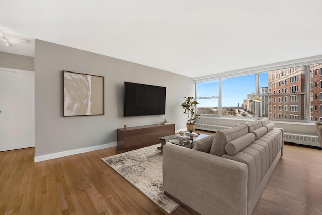 living area with radiator, wood finished floors, and baseboards