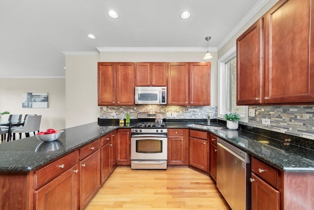 3443 N Lincoln Ave Unit 4A, Chicago, IL 60657 - kitchen featuring appliances with stainless steel finishes, a peninsula, light wood-type flooring, dark stone countertops, and crown molding