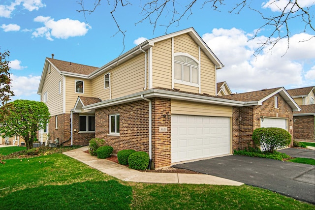 view of front facade with brick siding, driveway, a front yard, and a garage