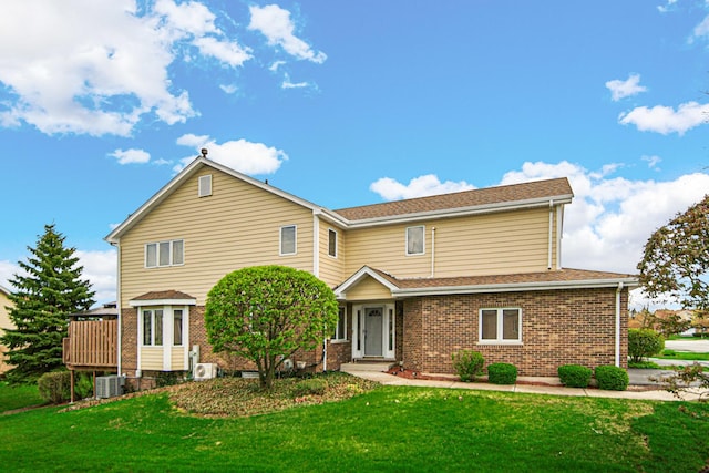 traditional home with a shingled roof, a front lawn, brick siding, and central AC unit