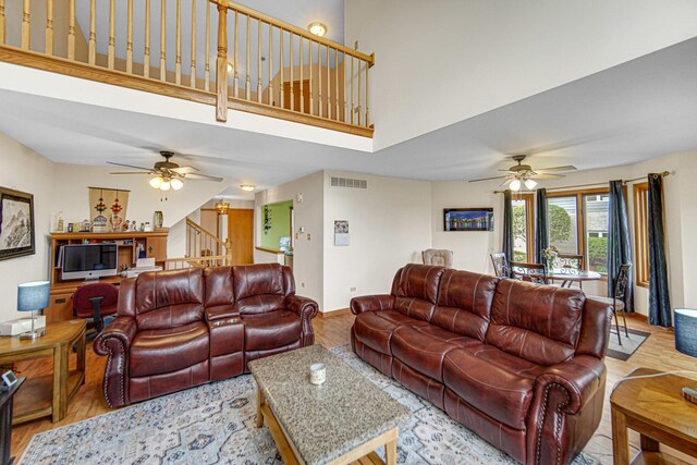 living area featuring a ceiling fan, visible vents, wood finished floors, and baseboards