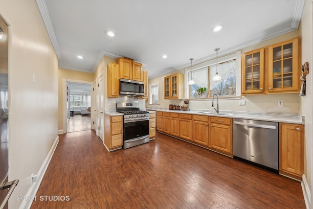 kitchen with a sink, dark wood-style flooring, light countertops, appliances with stainless steel finishes, and crown molding