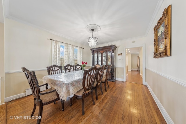 dining area featuring a chandelier, baseboards, ornamental molding, and hardwood / wood-style flooring