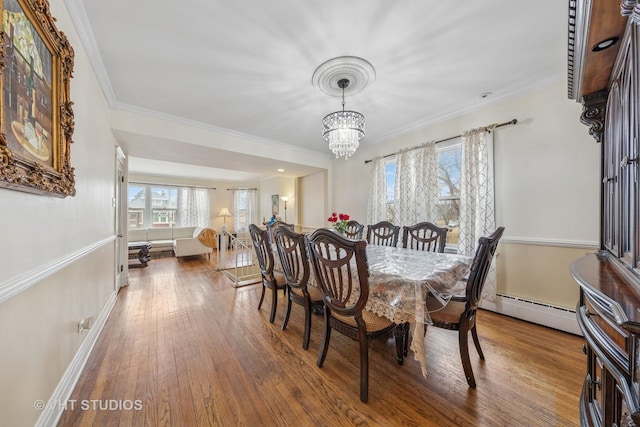 dining area featuring baseboards, a notable chandelier, hardwood / wood-style flooring, baseboard heating, and crown molding
