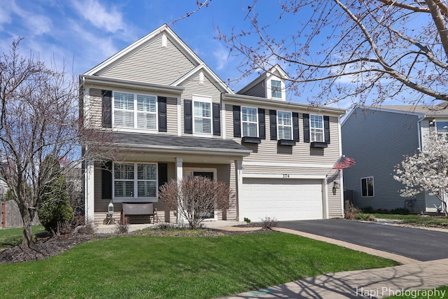 view of front of home with a porch, driveway, an attached garage, and a front lawn