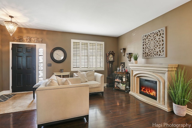 living area with a healthy amount of sunlight, dark wood-style flooring, baseboards, and a glass covered fireplace