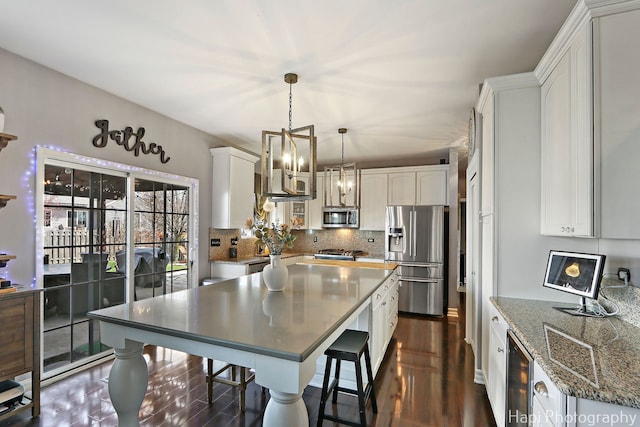 kitchen with a center island, backsplash, white cabinets, stainless steel appliances, and beverage cooler