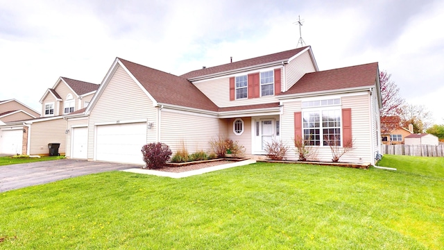 traditional-style house with driveway, fence, a shingled roof, and a front lawn