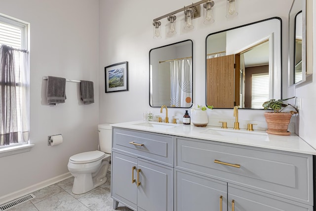 bathroom featuring toilet, baseboards, and double vanity