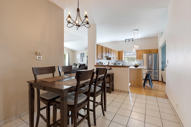 dining space featuring a chandelier, lofted ceiling, light tile patterned floors, and baseboards
