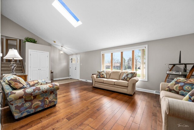 living area with hardwood / wood-style flooring, baseboards, and lofted ceiling with skylight