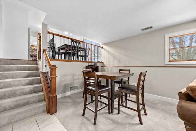 dining space featuring stairway, baseboards, visible vents, and carpet