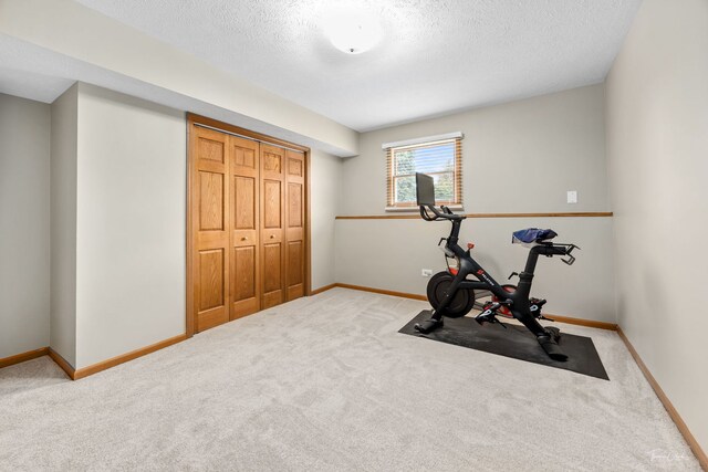 exercise area featuring carpet, a textured ceiling, and baseboards