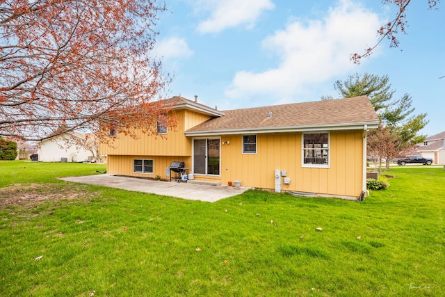 rear view of property with a yard, a patio area, and a shingled roof